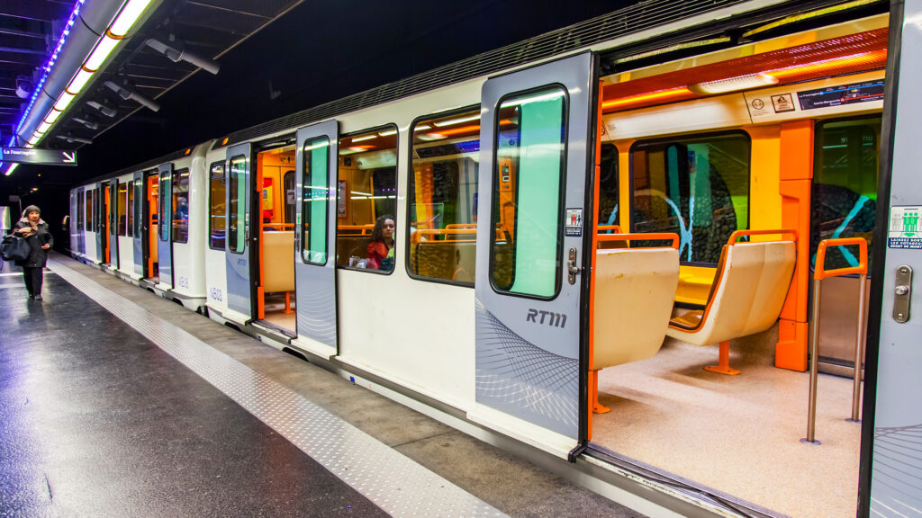 A high-angle view of commuters standing on a subway platform as a train arrives.