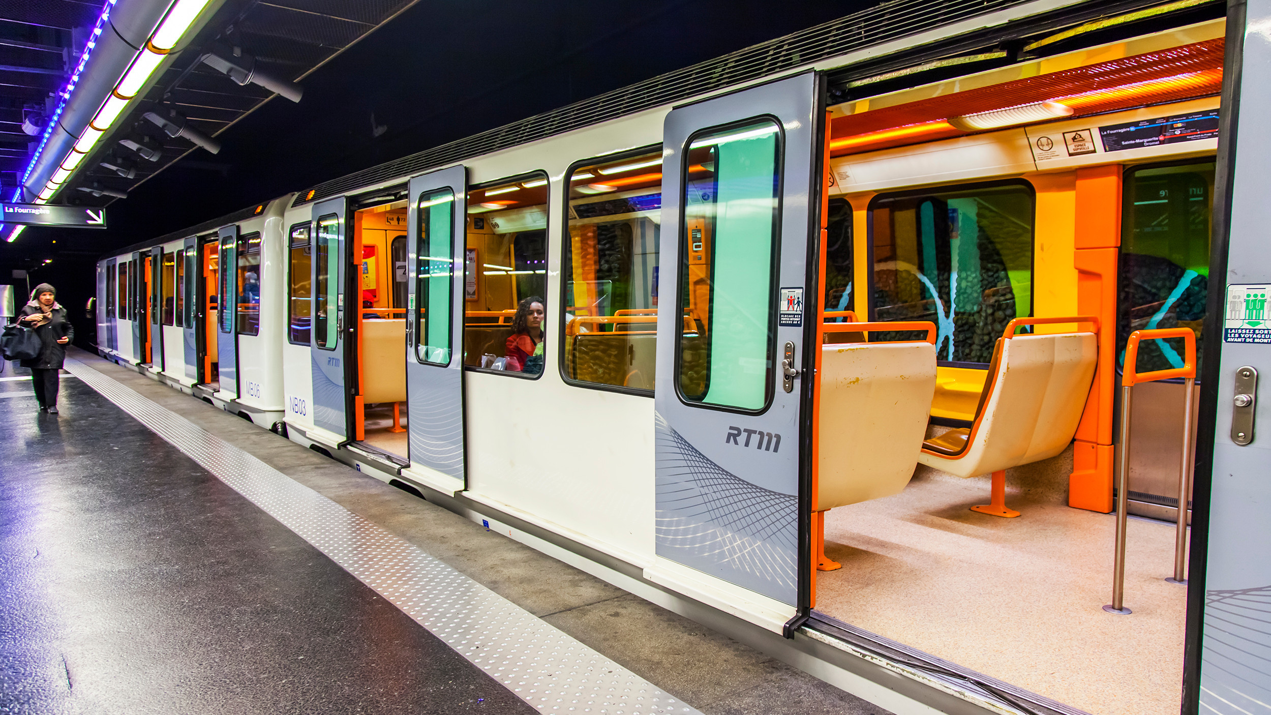 A high-angle view of commuters standing on a subway platform as a train arrives.